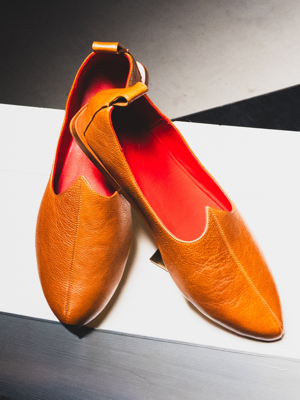 Pair of brown pointed-toe rajasthani luxury mojri loafer with red lining on a white surface.