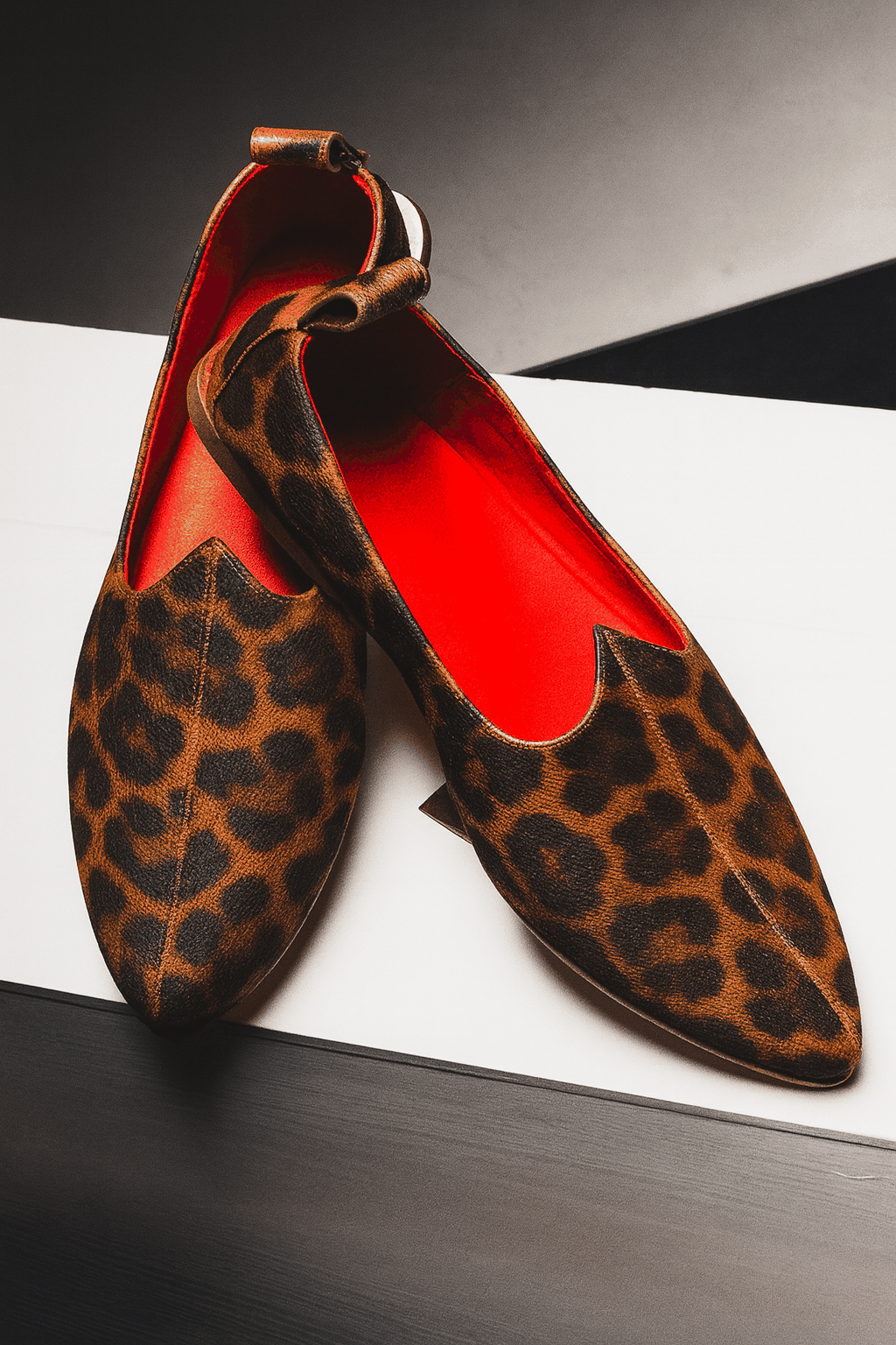 Leopard print shoes with red interior on a white surface. Handmade in Italy, Indian inspired Mojri loafers.