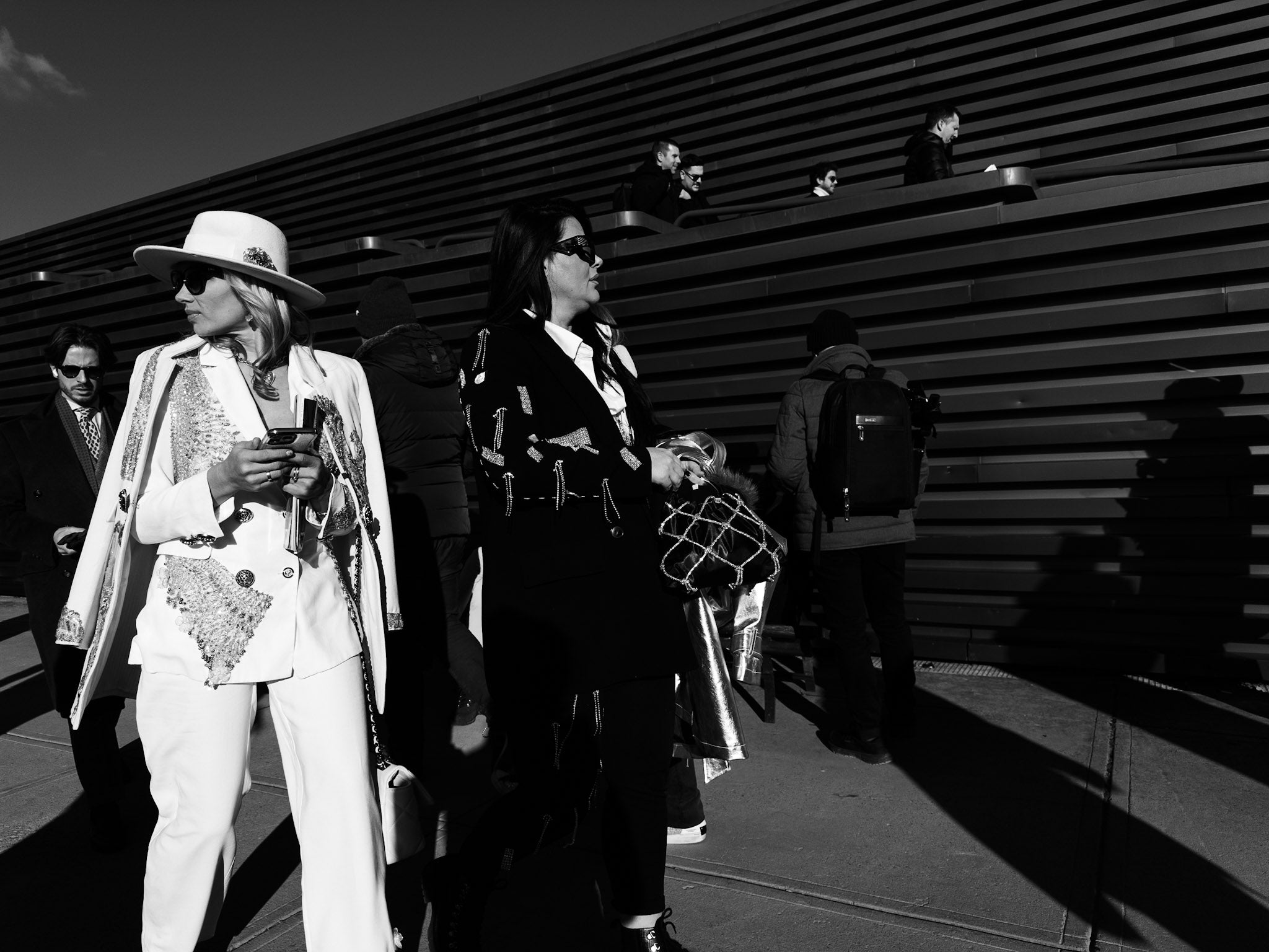 Two people in formal attire standing against a metallic wall.