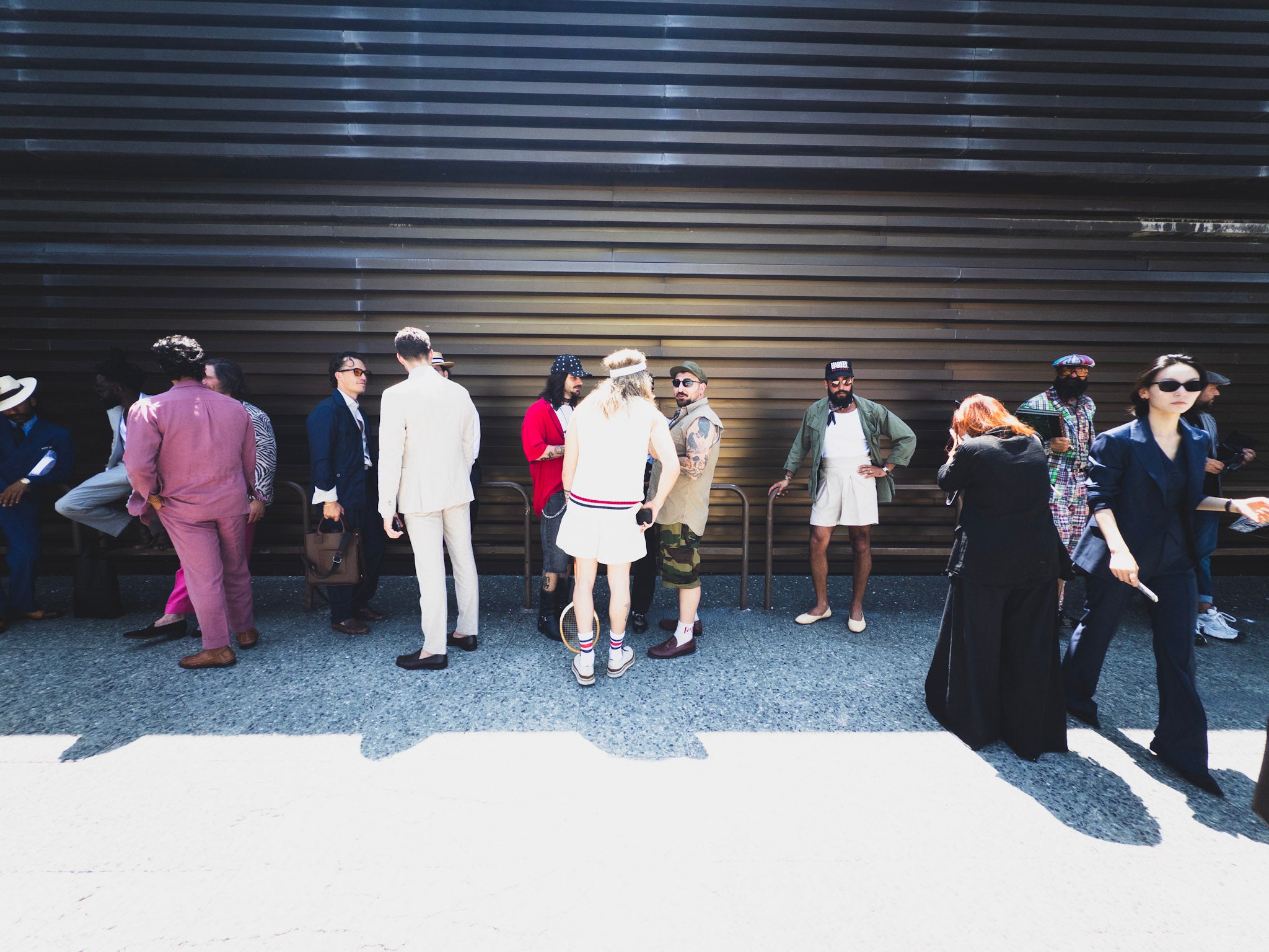 Group of people standing in front of a metallic wall at Pitti Uomo 108