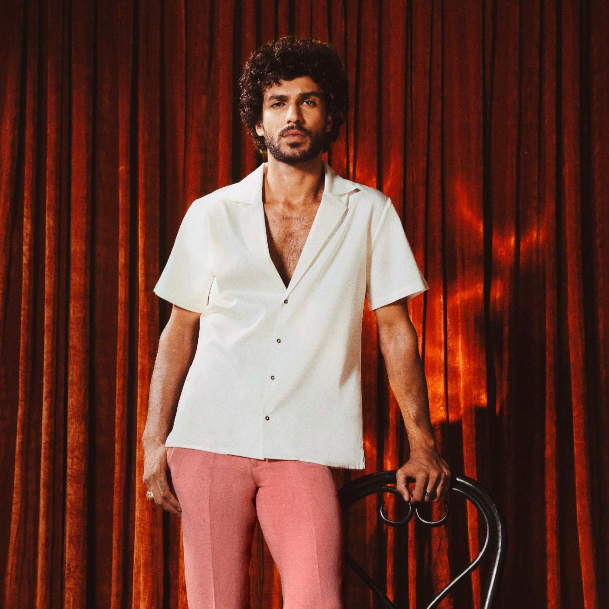 Model wearing Ivory white slim-fit 10 Paisa Shirt with notch lapel, short sleeves, deep neckline, and custom coin-inspired buttons