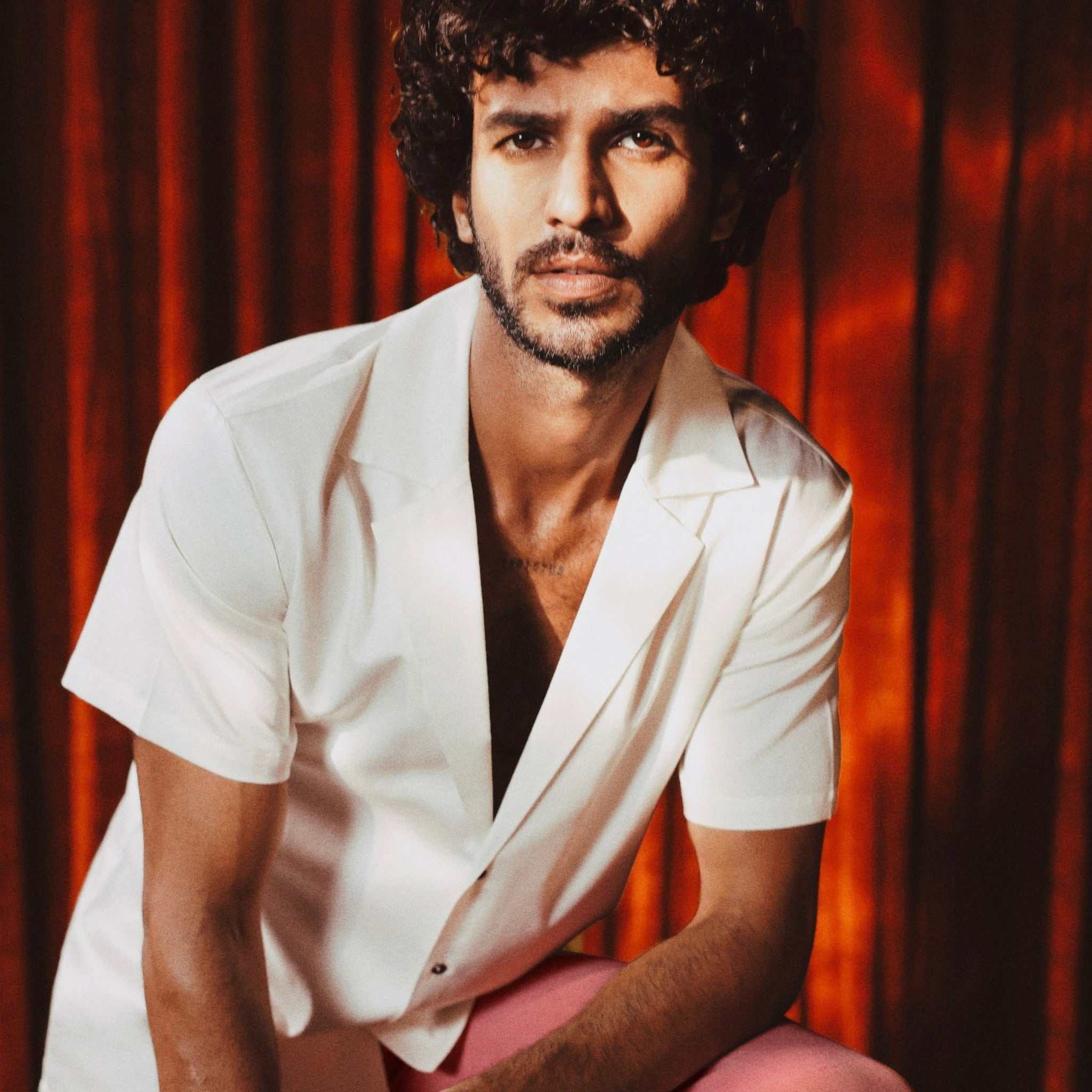 Model wearing Ivory white slim-fit 10 Paisa Shirt with notch lapel, short sleeves, deep neckline, and custom coin-inspired buttons