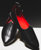 Handmade Black Rajasthani luxury Mojri with red lining on a white surface and black background