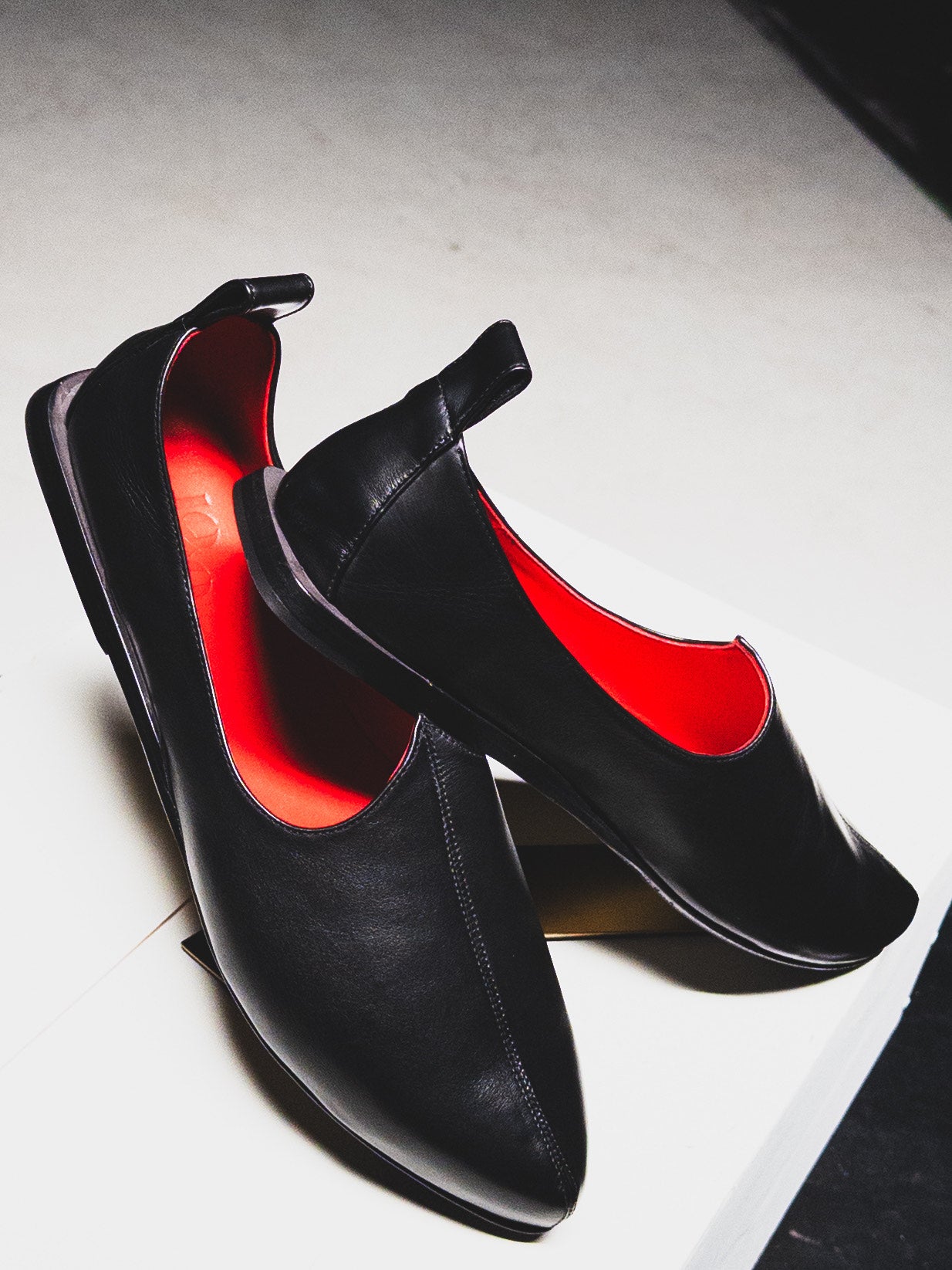 Handcrafted Black loafers with red interior on a white background. Designer  Rajasthani Mojri